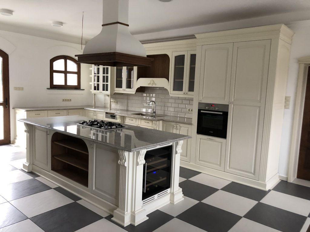 White paneled kitchen with checkerboard floor and freestanding range.