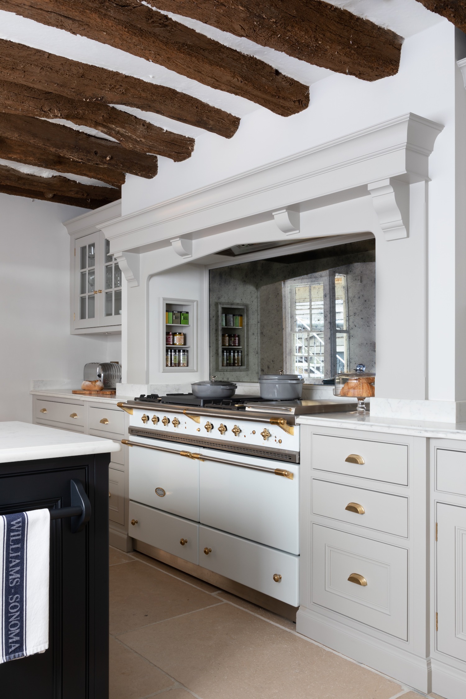 White kitchen with black range and beams.