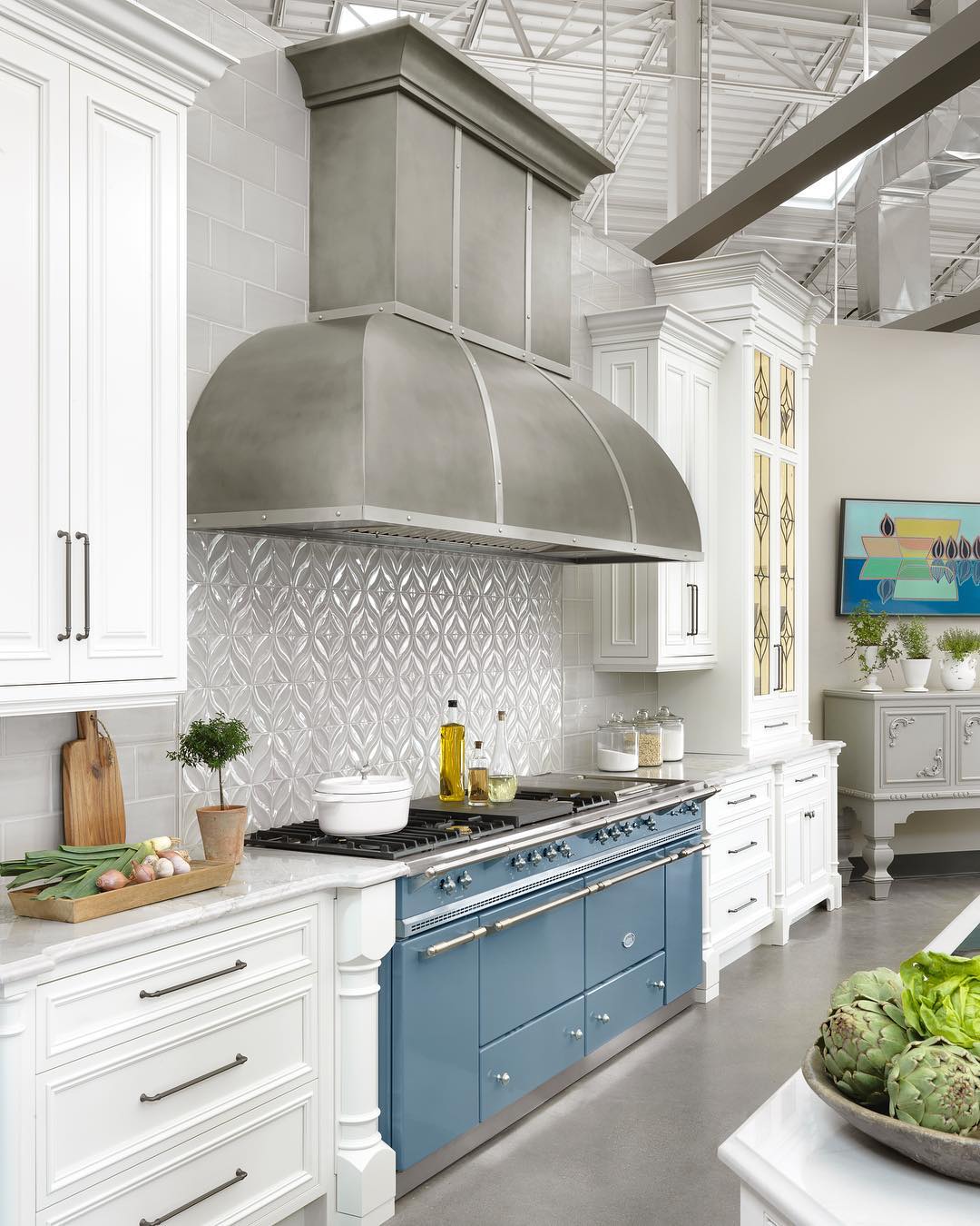 White kitchen with broad island and open shelves.