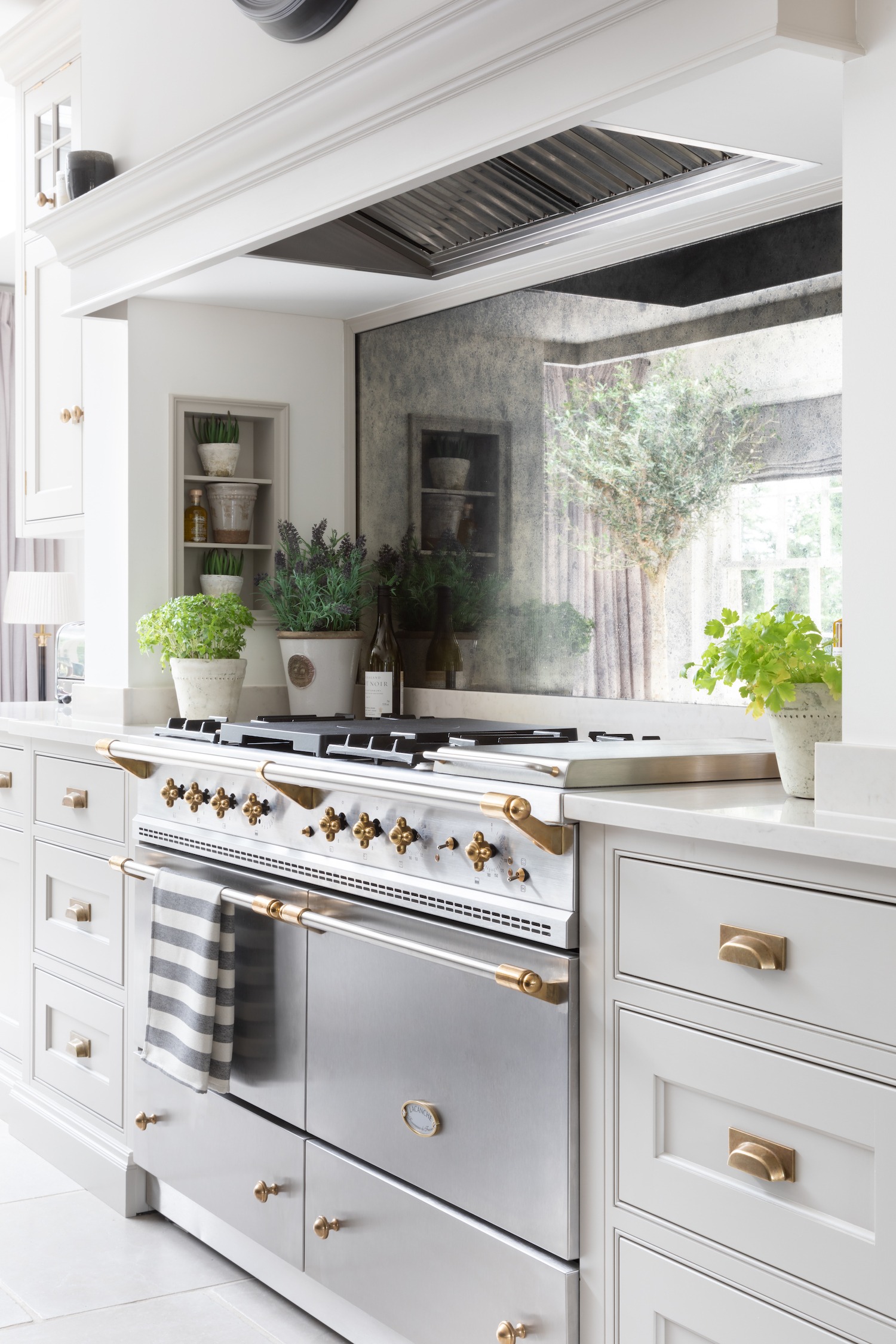 White kitchen with dark range and marble wall.