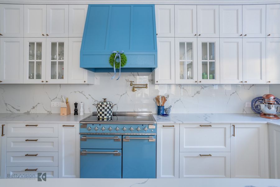 White kitchen with blue hood and range.