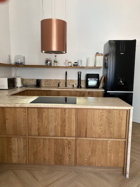Close view of wood drawers and white counter with a copper pendant.
