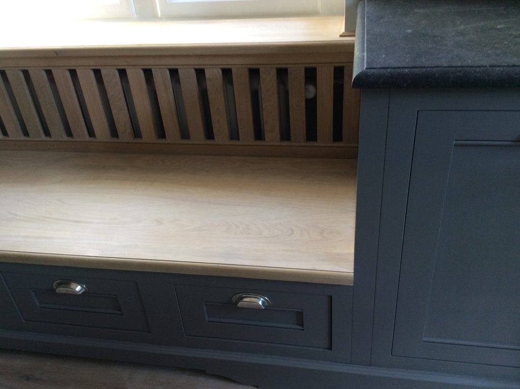 Wood window bench with dark drawers.